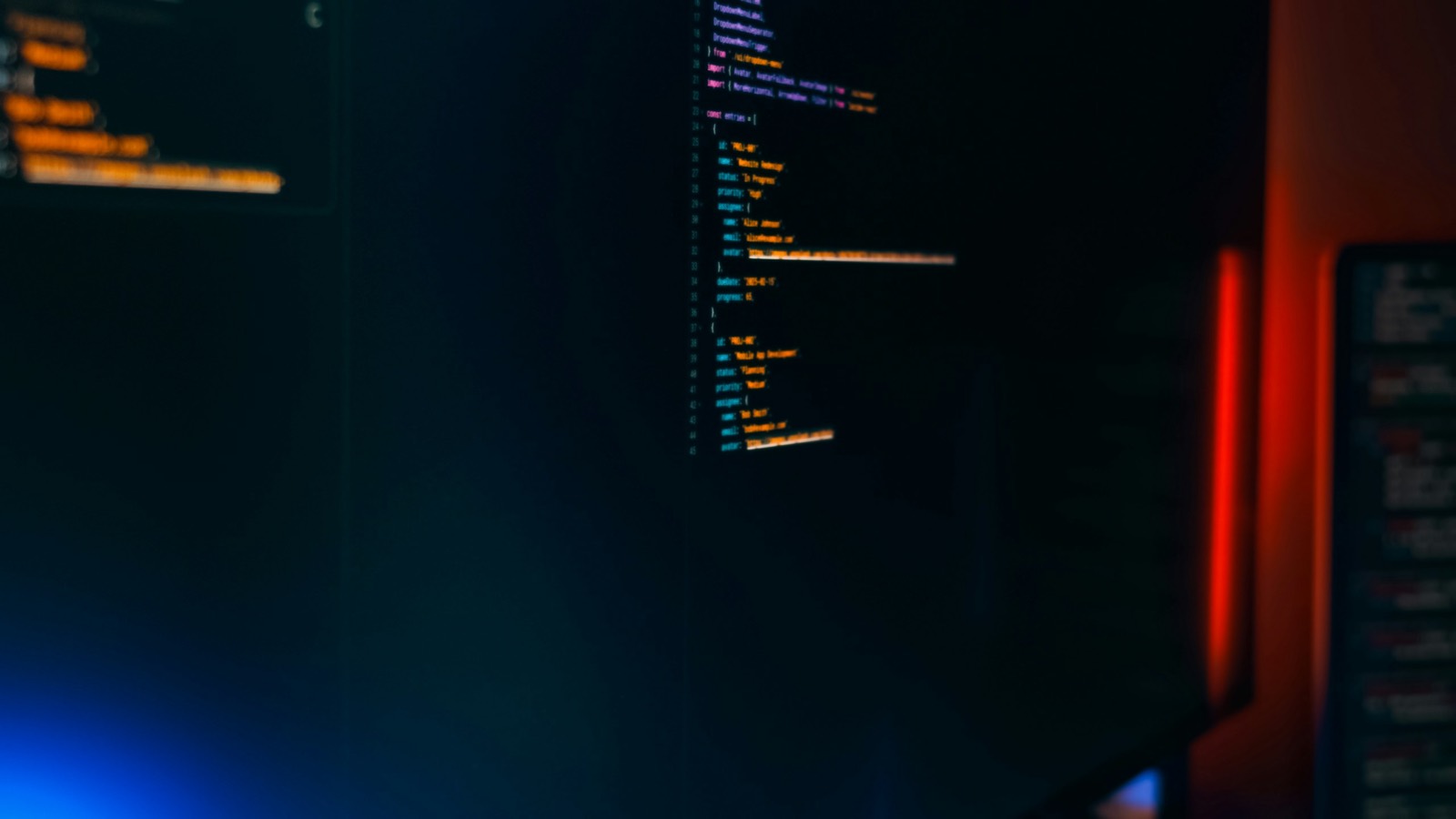 A dark monitor displaying source code, lit by ambient LED light